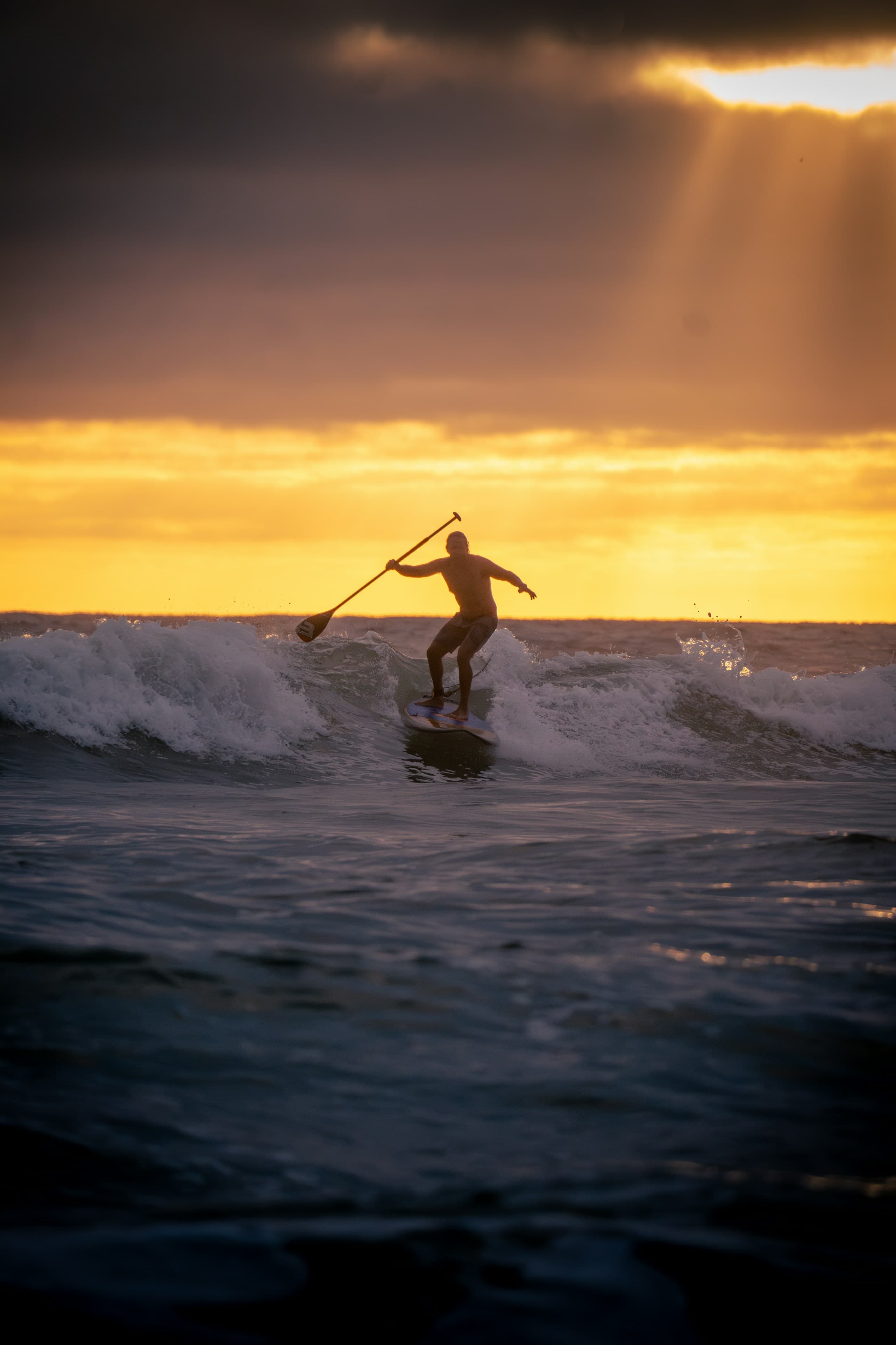 A surfer riding a wave at golden hour